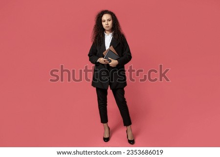 Attractive young girl in glasses and a black suit on a red background
