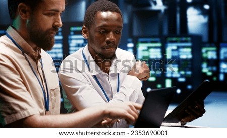 Coworkers overseeing supercomputers helping businesses manage databases, host websites and store files. Technicians auditing server room infrastructure used for high performance computing Royalty-Free Stock Photo #2353690001
