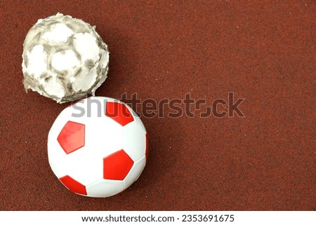 Two football balls on playground rubber coating
