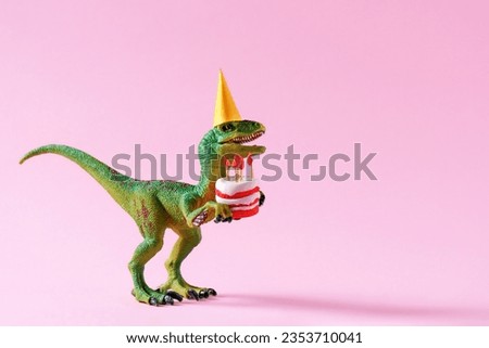 Cute happy green dinosaur in birthday hat holding cake with flaming candles on pastel pink background. Copy space. Minimal art birthday card idea. Royalty-Free Stock Photo #2353710041