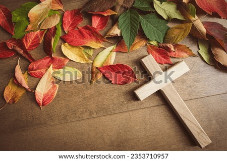 Cross on a wood background with an autumn leaf border