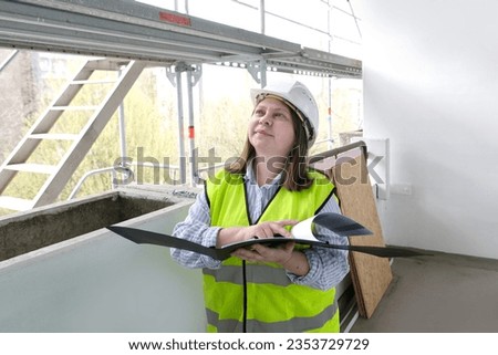 experienced woman architect, constructor engineer in protective white helmet controls the object at the construction site for the renovation of buildings, civil engineering concept Royalty-Free Stock Photo #2353729729