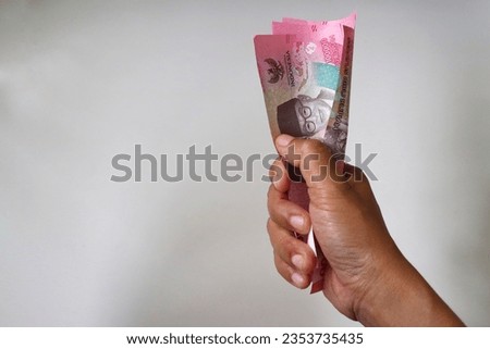 Money in the hand (Hand with money, Hand holding Banknotes). IDR bank notes denomination one hundred thousand.