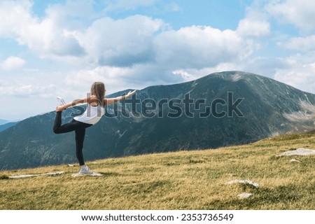 A beautiful young woman relaxes practicing meditation and yoga exercises in nature in a mountain landscape. Relaxation and meditation on vacation.