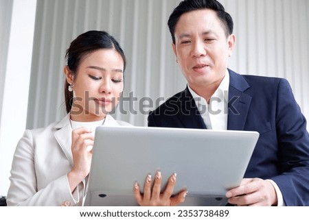 Businessman and businesswoman working at desks in the office.