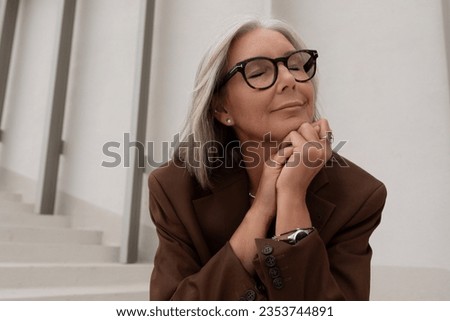 a gray-haired middle-aged woman with a bob haircut is dressed in a jacket and trousers enjoying freedom on the street Royalty-Free Stock Photo #2353744891