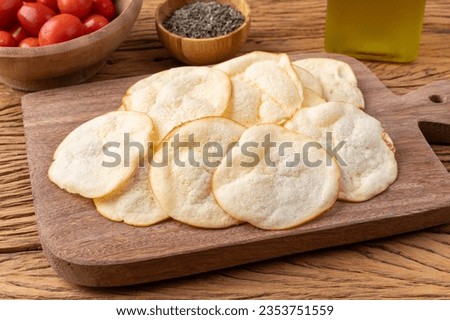 Smoked provolone cheese chips in a bowl with cherry tomatoes and oregano over wooden table. Royalty-Free Stock Photo #2353751559