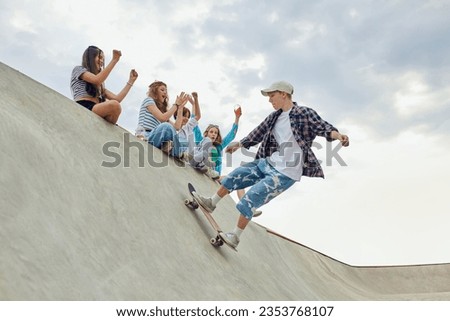 Friends, teengaers meeting at skate park for active leisure time. Boy in casucl clothes skateboarding on ramp. Concept of youth culture, sport, dynamic, extreme, hobby, action and motions, friendship Royalty-Free Stock Photo #2353768107