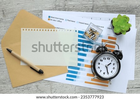 blank notepad with table clock and pen on wooden table, business concept