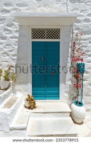 Colorful traditional house entrance of the Cyclades islands, with a wooden green door and a white washed walls, as seen in Syros island, in Cyclades islands, Greece, Europe. Royalty-Free Stock Photo #2353778915