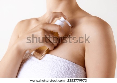 Cropped image of female body in towel, applying body moisturizing gel after shower against white studio background. Concept of female beauty, skin care, cosmetology and cosmetics, health, ad