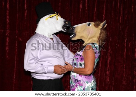 Photo Booth. Unidentifiable People wear Horse Head Masks and pose and play while their pictures are taken in a Photo Booth. Party Photo Booth. Wedding Photo Booth. Holiday. Horsing Around. Fun 
