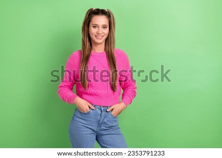 Photo of cheerful satisfied woman with ponytails hairdo dressed pink sweater hold arms in pockets isolated on green color background