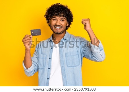 Photo of funky lucky guy dressed denim jacket rising fist bank plastic card isolated yellow color background