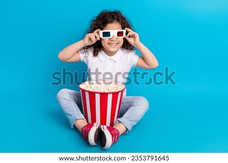 Photo of positive girl kid have big popcorn bucket enjoy watching movies isolated blue color background