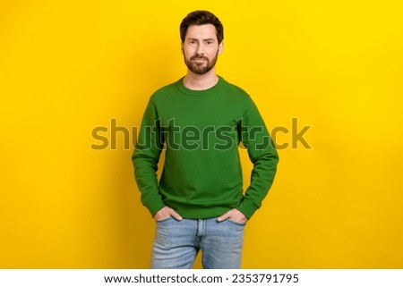 Photo of attractive masculine bearded man guy posing camera wearing green sweatshirt blue jeans isolated yellow color background Royalty-Free Stock Photo #2353791795
