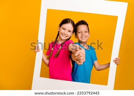 Photo of pretty friendly preteen schoolkids dressed t-shirts holding hands arms taking photo isolated yellow color background