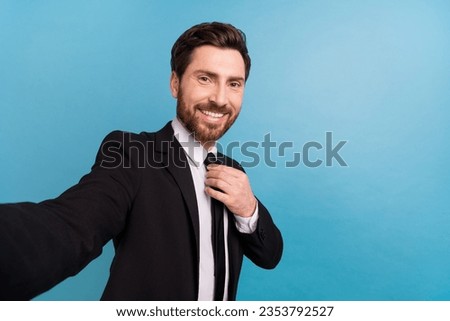 Photo of handsome positive teacher guy dressed black suit taking selfie fixing tie empty space isolated blue color background