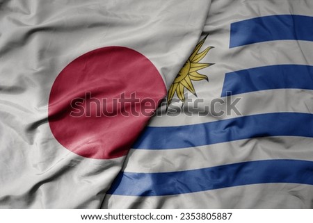 big waving national colorful flag of japan and national flag of uruguay . macro