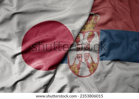 big waving national colorful flag of japan and national flag of serbia . macro
