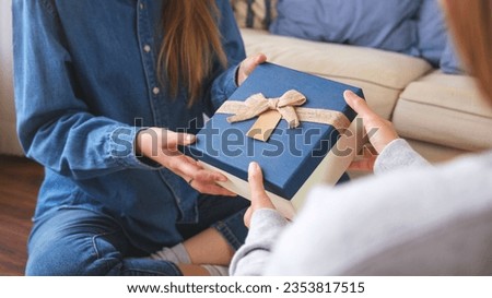 Closeup image of a couple women receiving and giving a gift box to each other