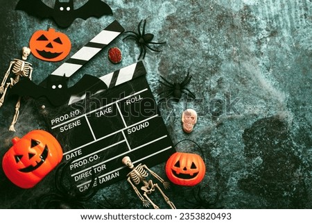 Halloween movies concept. Movie clapperboard with funny halloween pumpkin,skeletons and spiders over grunge background. Halloween concept background