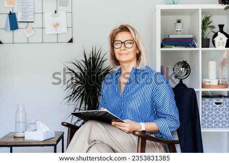 Professional Psychotherapy. Successful female Psychologist Smiling To Camera Sitting On armchair In Office. Mature 50s middle-age professional portrait of teacher, coach, mentor, therapist, counselor Royalty-Free Stock Photo #2353831385