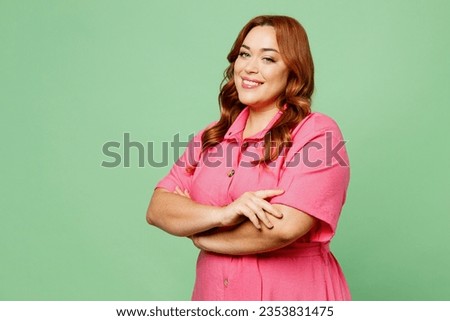 Side view smiling happy cheerful young chubby overweight redhead woman wear casual clothes pink dress hold hands crossed folded isolated on plain pastel light green color background. Lifesyle concept Royalty-Free Stock Photo #2353831475