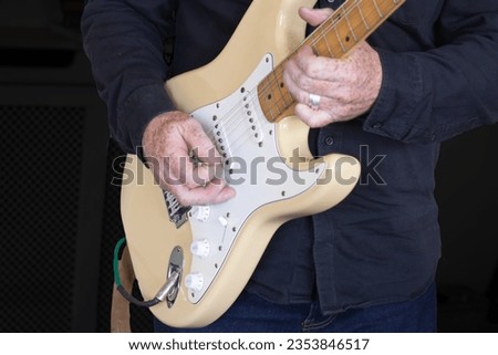 Close up of man playing an electric guitar with a green pic