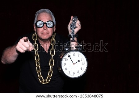 Photo Booth. A man wears Crazy Glasses a Gold Chain and holds an Alarm Clock while in a Photo Booth. People love crazy props and to pose in Photo Booths at Parties. Photo Booth take and Print Pictures