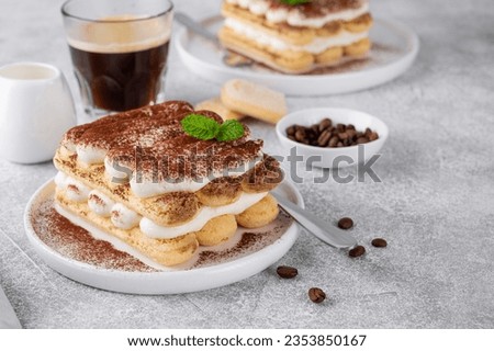 Tradition italian layered dessert tiramisu with mascarpone cream and biscuits on a white plate with cup of coffee on a gray concrete background Royalty-Free Stock Photo #2353850167