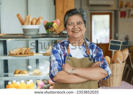 Asian elderly woman standing with arms crossed and smiling happily. After using pension after retirement Let's open small business coffee shop. in order to income in old age business can be forwarded Royalty-Free Stock Photo #2353852035