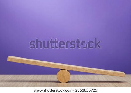 Empty wooden scales on a purple background. The concept of equilibrium and balance. High quality photo with copy space.