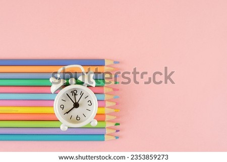 School background with colored pencils of delicate tones and an alarm clock on a pink background.The concept of products for creativity, artists, schoolchildren.Back to school.Copyspace Royalty-Free Stock Photo #2353859273