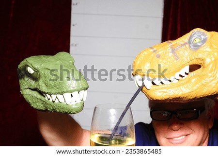 Photo Booth. A man poses for his picture to be taken with Dinosaur Head Puppets while in a Photo Booth. Everyone even Dinosaurs love a Photo Booth at Parties and Events. Pictures get printed for you.