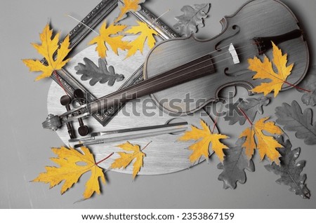 Violin, bow, picture frame, brushes and autumn maple leaves on grey. art attributes.