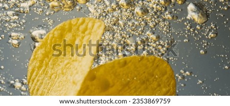 Deep fried potato chips under golden oil water. Frying rounded potatoes chip with hot boiling oil bubbles. Fast food and snack. Underwater cooking oily french fries or potatos chips in oils background Royalty-Free Stock Photo #2353869759