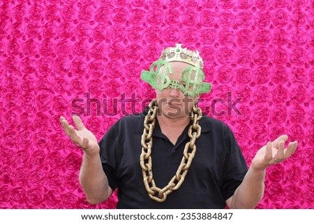 Photo Booth. A man Smiles and Laughs as he poses for his picture to be taken while in a Photo Booth at a Party. People love to pose with Props and their friends in  Photo Booths at Parties. Holidays. 