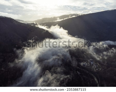 View of the autumn village in the mountains through the clouds