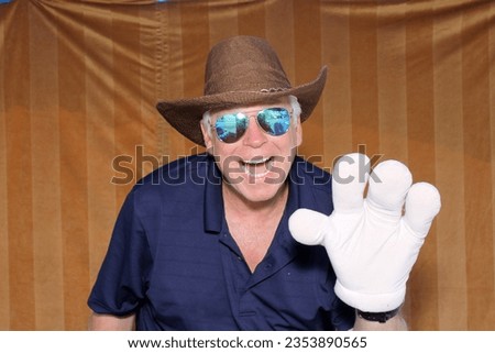 Photo Booth. A man poses and Smiles with props while having his picture taken in a Photo Booth at a party. People love photo booths at parties and events. Everyone gets printed pictures and memories. 