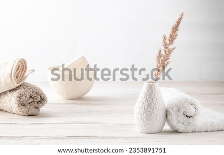 Bathroom interior. Soft towels, a cup of soap and a vase with a dry flower. Minimalism style, high key photo