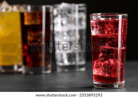 Glass of refreshing soda water with ice cubes on grey table, closeup. Space for text