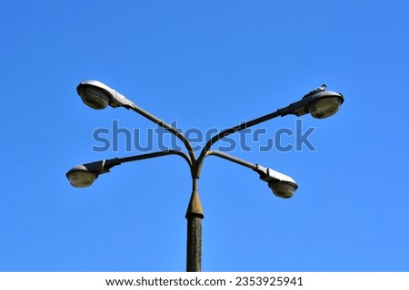 Strong with lots of power old quadruple lantern on a concrete pole top views of lamps against a blue sky without clouds Royalty-Free Stock Photo #2353925941