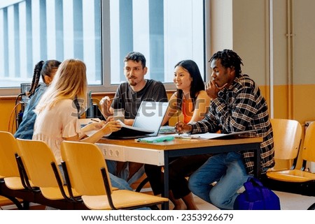 multiracial group of young man and women studying together with class notes and a laptop at the table in a university campus. Royalty-Free Stock Photo #2353926679