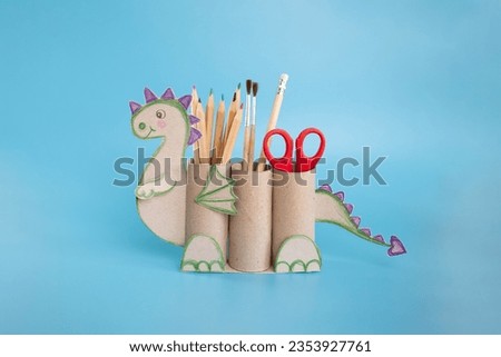 dragon shape a pencil holder made out of toilet paper and a pair of scissors, educational and craft activity Royalty-Free Stock Photo #2353927761