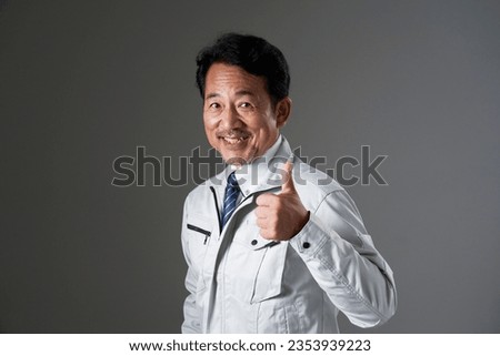 Asian middle aged worker thumbs up gesture in black background
