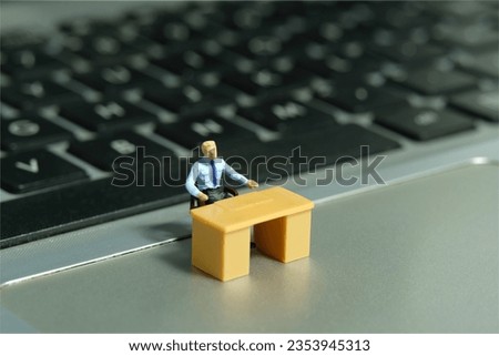 Miniature tiny people toy figure photography. A tired businessman seat in the desk, stunned above notebook. Image photo