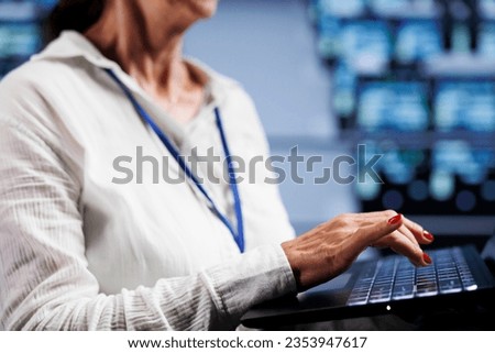System admin working on laptop, setting up high bandwidth dedicated multiplayer gaming servers in high tech facility to accommodate more traffic from worldwide locations and avoid lag, close up Royalty-Free Stock Photo #2353947617