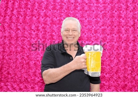 Photo Booth. A man Smiles as he enjoys a Giant Mug of Beer while having his pictures taken in a Photo Booth at a Party.
Photo Booths are popular at parties of all types around the world. Beer.