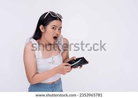A young asian woman is amazed to find a lot of cash inside her wallet. Concept of money savings. Isolated on a white background. Royalty-Free Stock Photo #2353965781